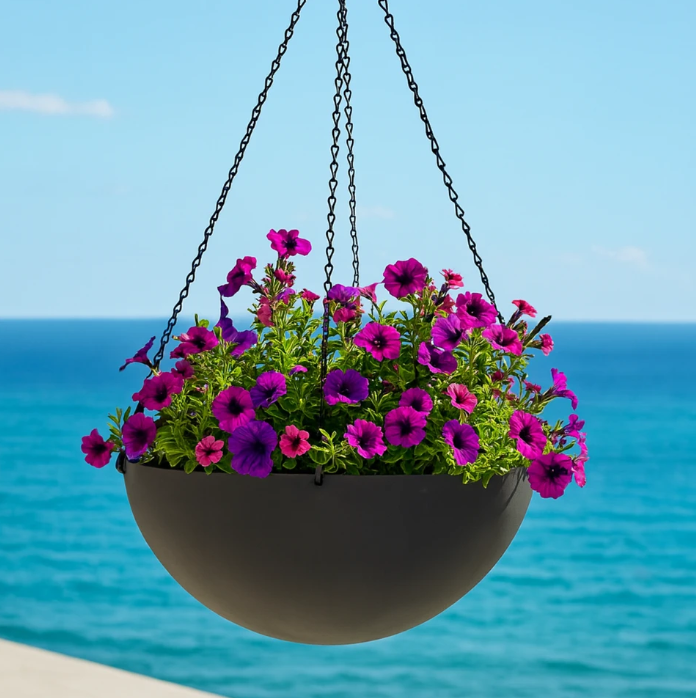 A hanging basket with a variety of flowers hangs from a porch with ocean in background.